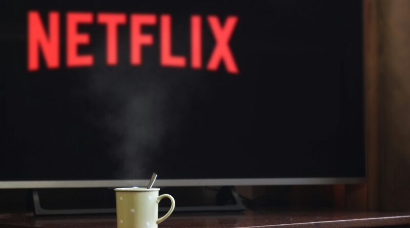 A steaming mug on a table in front of a TV displaying Netflix, creating a cozy indoor atmosphere.
